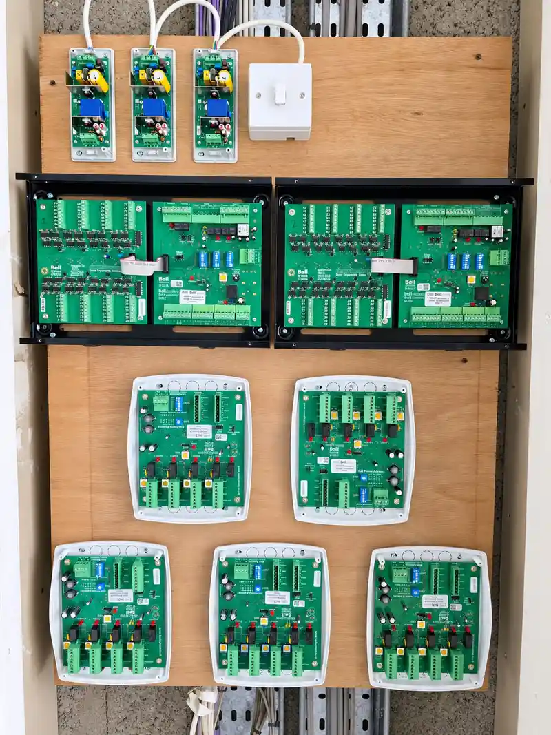 Plywood backboard in a cupboard with three power supplies, two banks of control boards and five distribution units, covers off.