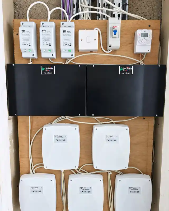 The same backboard finished, with Bell power supplies, an isolator, a timer and branded black covers over the control boards.