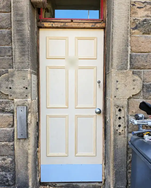 New unpainted six-panel timber door with a kick plate, fitted in the same stone doorway.