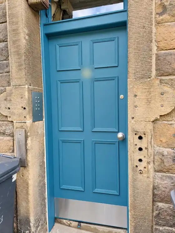 The painted teal-blue door straight on, in its stone surround with a fanlight above.