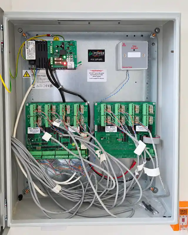 Open grey enclosure showing door entry control boards, a power supply and neatly labelled cables.