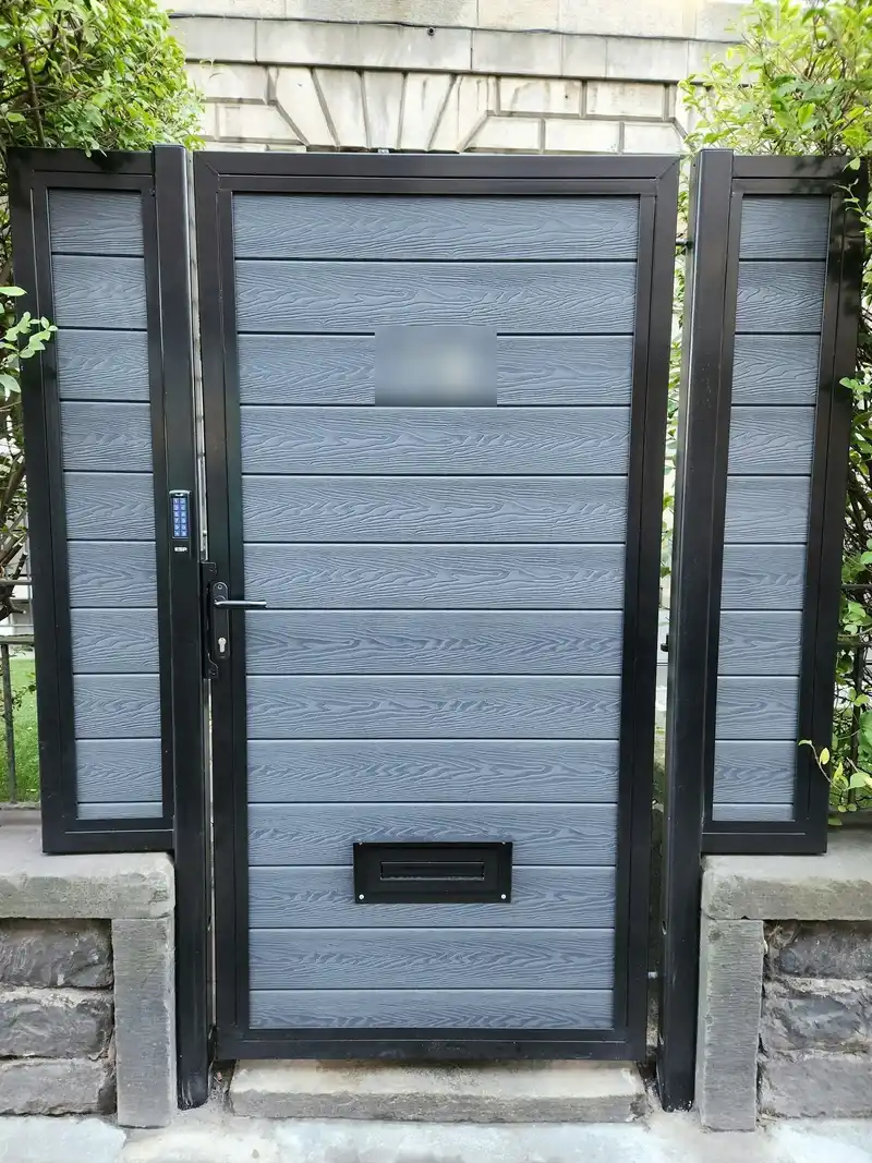 Grey composite garden gate in a black frame with a letter plate, a lever handle and a keypad on the frame.