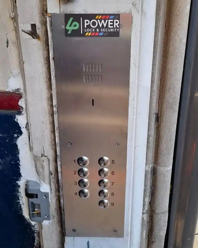 New stainless steel door entry panel with nine buttons fitted into an old stone doorway.