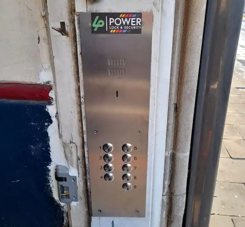New stainless steel door entry panel with nine buttons fitted into an old stone doorway.