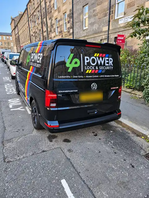 Rear of the black Power Lock & Security van on a cobbled tenement street, logo and service list on the back window.
