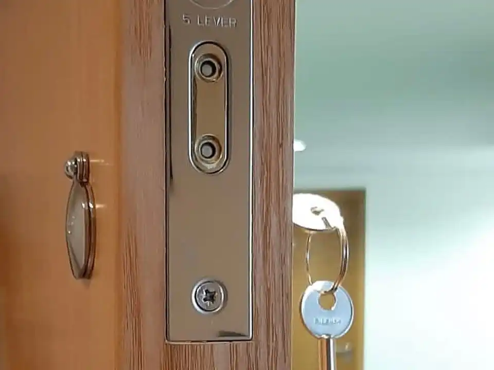 Forend of a Yale five-lever mortice lock on an oak-effect door, with a key hanging from the lock.