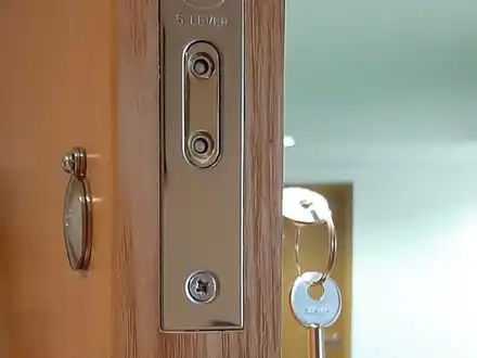 Forend of a Yale five-lever mortice lock on an oak-effect door, with a key hanging from the lock.
